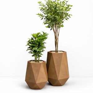 May include: Two brown geometric planters with green plants. The planters have a faceted design and are filled with small stones. One planter is smaller than the other. The background is white.