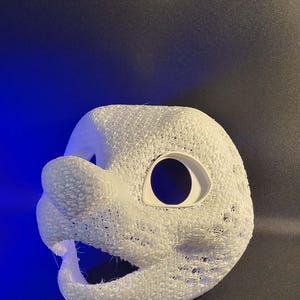 May include: A white, textured mask with large eye openings and a snout. The mask appears to be 3D-printed, with a porous surface. The mask is likely for costume or cosplay purposes.