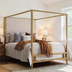 Könnte beinhalten: Ein goldfarbenes Himmelbett mit einem neutralfarbenen Kopfteil und Bettwäsche. Das Bett ist mit verschiedenen Kissen in Grau-, Schwarz- und Brauntönen geschmückt. Eine braune Decke mit Fransen ist über dem Fußende des Bettes drapiert.