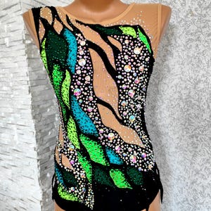 May include: A black, green, and blue leotard with a leaf-like design. The leotard is embellished with iridescent rhinestones and features a nude mesh overlay on the shoulders and upper chest. The design is symmetrical and suitable for gymnastics or dance.