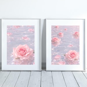 以下が含まれることがあります： ピンクのバラが花びらとともに水面に浮かぶ、2つの額装されたアートプリント。水面はキラキラと輝く効果があります。フレームは白で、背景は明るい木製の床です。