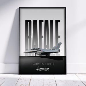 Pode incluir: Pôster emoldurado com um caça Dassault Rafale cinza. A palavra "RAFALE" é exibida em letras grandes, em negrito, em preto e branco. Abaixo do avião, o texto diz "READY FOR DUTY" e "DASSAULT AVIATION".
