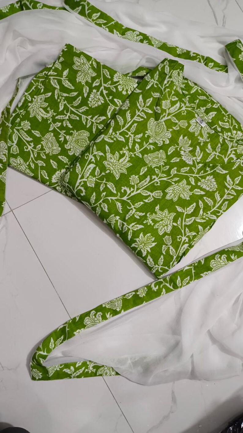 Puede incluir: Tela verde con un estampado floral blanco, doblada y dispuesta con tela blanca y ribete a juego con estampado verde. La tela es probablemente para ropa o decoraci&oacute;n del hogar.