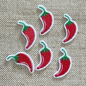Pode incluir: Seis emblemas bordados individuais de pimentas. Cada emblema apresenta uma pimenta vermelha brilhante com um caule verde e uma borda branca, exibindo um trabalho de fio detalhado e uma forma curva, dispostos num padrão disperso.