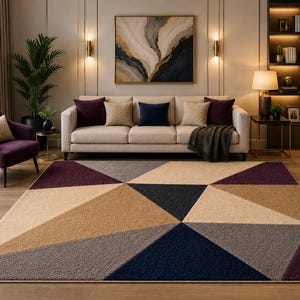 May include: A rectangular area rug featuring a geometric pattern of large triangles in shades of deep purple, navy blue, beige, and gray. The rug has a textured, plush surface and is positioned on a light wood floor in front of a sofa.