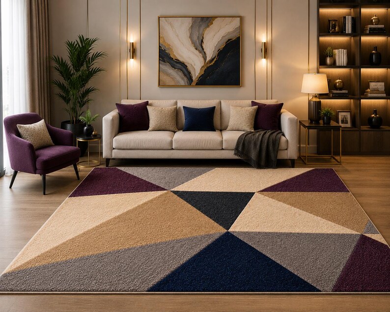 May include: A rectangular area rug featuring a geometric pattern of large triangles in shades of deep purple, navy blue, beige, and gray. The rug has a textured, plush surface and is positioned on a light wood floor in front of a sofa.