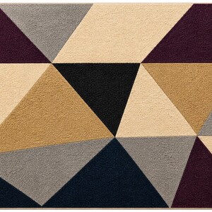 May include: A rectangular area rug featuring a geometric pattern composed of various triangles in shades of deep purple, black, dark navy blue, light beige, and medium gray. The rug has a textured surface and a thin, solid-colored border.