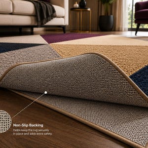 May include: A rectangular area rug featuring a geometric pattern in shades of navy blue, tan, gray, and deep purple. The rug has a textured pile surface and a tan fabric border. A corner is folded back to reveal a textured, non-slip backing material.