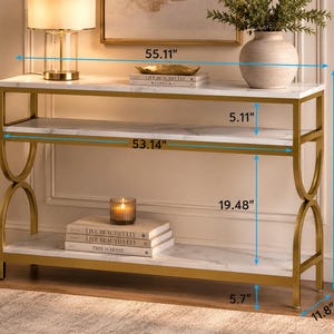 May include: A gold metal and marble console table. The table has two shelves and curved side supports. The top shelf is 55.11 inches long, and the table is 35.4 inches tall. The bottom shelf is 53.14 inches long.