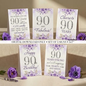 May include: A set of five 12.7 x 17.8 cm signs with a purple floral design, celebrating a 90th birthday. Each sign has a different message, including "90 and Fabulous!" and "Cheers to 90 Years."