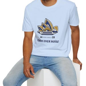 May include: Pale blue t-shirt with a navy and gold graphic of the Sydney Opera House. The text "FORM OVER NOISE" is below the graphic. The shirt is made of a soft material.