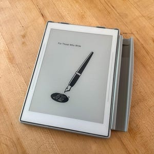 May include: A white digital tablet with a grey side attachment. The screen displays the text "For Those Who Write" above a graphic of a fountain pen and a black oval containing the word "SUPER NOTE" in white capital letters.