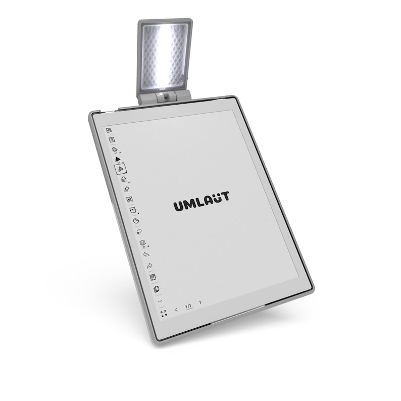 May include: A grey e-reader with an integrated light and the word "UMLAUT" displayed on the screen. The e-reader is rectangular with a slim bezel and a light fixture at the top.