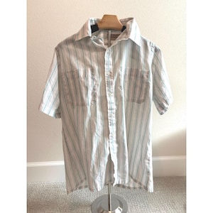 Op de afbeelding: Een witte keramische mok met een zwart handvat en de tekst "But First, Coffee" in een zwarte, vette letter. De mok staat op een wit oppervlak.