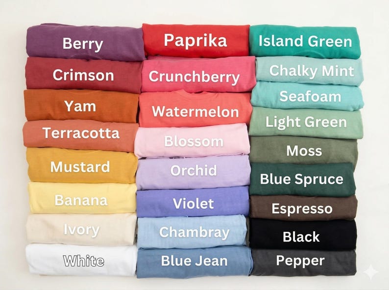 May include: A collection of folded t-shirts in various colors, including Berry, Paprika, and Island Green. Each shirt is labeled with its color name in white text. The shirts are neatly stacked, showcasing a range of hues.