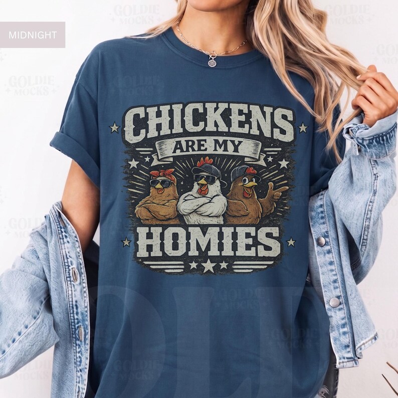 May include: Midnight blue t-shirt with the text "CHICKENS ARE MY HOMIES" in a distressed font. The graphic features three cartoon chickens wearing sunglasses and bandanas. The shirt has rolled-up sleeves.