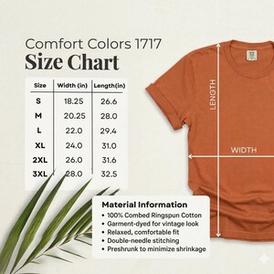 May include: A rust-colored t-shirt with a size chart and material information. The size chart shows measurements in inches for sizes S to 3XL. The material information states the shirt is 100% combed ringspun cotton and garment-dyed.