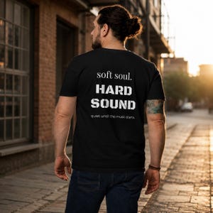 Könnte beinhalten: Ein schwarzes kurzärmeliges T-Shirt mit weißem Text auf der Rückseite. Der Text lautet soft soul. HARD SOUND quiet until the music starts. Das Shirt hat einen Rundhalsausschnitt und eine normale Passform, abgebildet von der Rückseite.