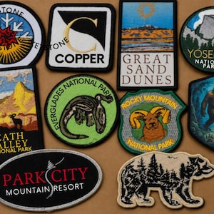 May include: A collection of ten embroidered patches featuring various designs including the Keystone logo, Copper, Great Sand Dunes, Yosemite National Park, Death Valley National Park, Everglades National Park, Rocky Mountain National Park, Bigfoot, Park City Mountain Resort, and a bear silhouette.