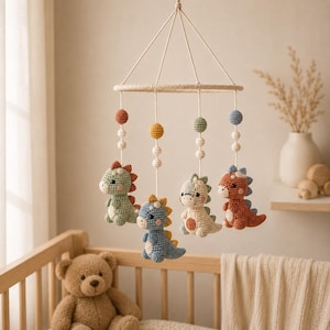 Può includere: Una giostrina sospesa con quattro dinosauri all'uncinetto nei colori verde salvia, blu, crema e terracotta. Ogni dinosauro pende da una cornice circolare tramite cordini bianchi decorati con piccole sfere all'uncinetto in toni abbinati.