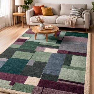 Puede incluir: Una alfombra rectangular con un patrón geométrico en tonos verdes, morados, azules y beige. La alfombra está colocada sobre un suelo de madera, con un borde beige. La alfombra está en un salón con un sofá y una mesa de centro.