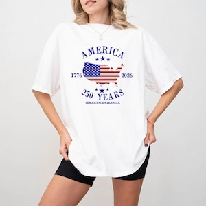 Könnte beinhalten: Weißes T-Shirt mit patriotischem Design. Die Grafik zeigt das Wort "AMERICA" über einer Karte der Vereinigten Staaten mit einem Flaggen-Design, die Jahre 1776 und 2026 sowie den Text "250 YEARS SEMIQUICENTENNIAL."