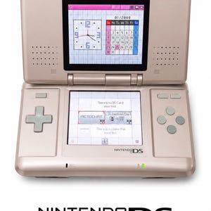 Peut inclure: Une console de jeu portable Nintendo DS couleur or rose métallique avec deux écrans. L'écran supérieur affiche une horloge et un calendrier, tandis que l'écran tactile inférieur montre le menu principal avec PictoChat et les paramètres.