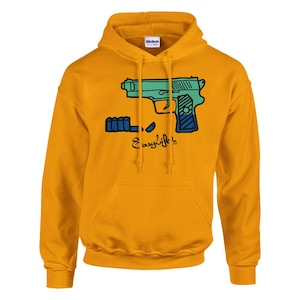 Può includere: Una felpa con cappuccio color giallo senape con una stampa grafica raffigurante una pistola color verde acqua e blu insieme a una fila di proiettili. Sotto la grafica, il testo "EasyLife" è stampato in un carattere corsivo nero.