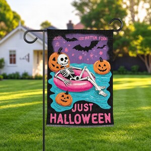 May include: A rectangular garden flag featuring a skeleton lounging in a pink pool float on blue water, surrounded by three orange jack-o'-lanterns and black bats against a purple starry sky. The text reads JUST HALLOWEEN in pink letters.