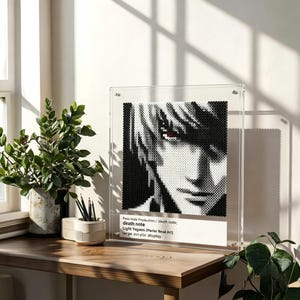 Op de afbeelding: Een zwart-wit gepixeleerd portret van Light Yagami uit Death Note, weergegeven in een groot acrylframe. Het kunstwerk is gemaakt met Perler-kralen. De tekst op het frame luidt "Pave Hide Production / death note: death note Light Yagami (Perler Bead Art) large acrylic display."