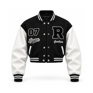 Op de afbeelding: Een zwart-wit varsity jack met een kort silhouet, witte mouwen en een zwarte body. De voorzijde toont het nummer 07, het woord League, een grote letter R en het woord fearless in wit borduurwerk met zilverkleurige drukknopen.