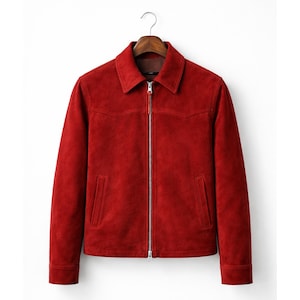 May include: A red suede jacket with a collared neckline and a silver zipper closure. The jacket has two front pockets and is hanging on a wooden hanger. The jacket's length is approximately 25 inches.