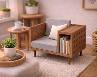 Puede incluir: Un sillón en miniatura de madera con asiento y respaldo tapizados en gris claro, un pequeño cojín blanco texturizado y un compartimento de almacenamiento lateral integrado que contiene varios libros con lomos coloridos y un panel lateral perforado.