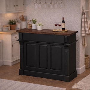 May include: A black kitchen island with a dark wood countertop. The island has a paneled front and is decorated with a bottle of wine, two wine glasses, and a small tray. The kitchen has white cabinets and a window.