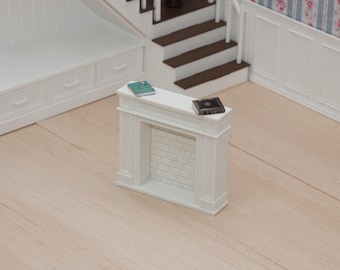 Puede incluir: Una chimenea en miniatura de color blanco con un interior de ladrillo falso, que presenta un pequeño libro de color verde azulado y un pequeño libro negro sobre la repisa superior. La chimenea se sitúa en una casa de muñecas con zócalos.