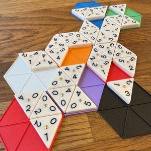 Peut inclure: Un jeu de puzzle géométrique coloré avec des pièces triangulaires et hexagonales. Les pièces sont de différentes couleurs, dont le rouge, l'orange, le violet et le noir. Chaque triangle comporte des chiffres et des points dorés.