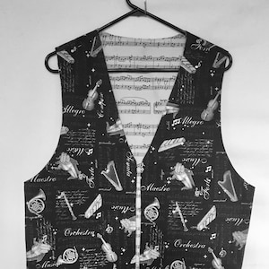 May include: Black vest with a musical theme. The vest is covered in a white print of musical instruments, sheet music, and musical terms like "Maestro", "Allegro", "Forte", and "Orchestra".