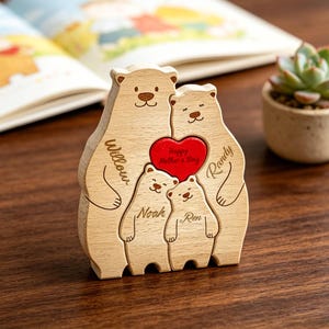 Può includere: Un puzzle in legno a forma di famiglia di orsi con due orsi grandi e due piccoli. Gli orsi sono incisi con i nomi Willow, Randy, Noah e Ren. Al centro è posizionato un cuore rosso con inciso il testo Happy Mother's Day.