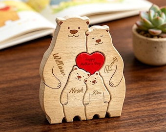 Puede incluir: Un rompecabezas de madera de una familia de osos con dos osos grandes y dos pequeños. Los osos tienen grabados los nombres Willow, Randy, Noah y Ren. Un corazón rojo está colocado en el centro con el texto Happy Mother's Day grabado.