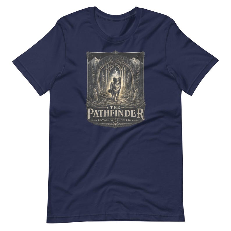May include: Navy blue t-shirt featuring a detailed graphic of a dog in a forest, with the text "THE PATHFINDER" and the words "LOYAL. WISE. WILD." The design is in shades of gray and beige.