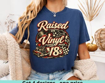 May include: Navy blue t-shirt with a retro graphic that reads "Raised on Vinyl and 80s." The design includes a vinyl record, a classic car, and musical notes. The shirt has a crew neck and short sleeves.