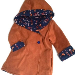 May include: A rust-colored hooded jacket with a blue and white fox print lining. The jacket has a single button closure and a relaxed fit.