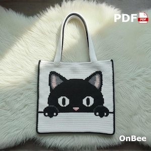 May include: A white crochet tote bag with a black cat face design. The cat has black ears, eyes, and paws, with pink accents. The bag has a black border and handles. The text "PDF" and "OnBee" are visible.