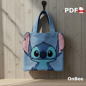 May include: A light blue crochet tote bag featuring a cartoon character with large ears and a friendly expression. The character is in shades of blue, pink, and black. The bag is hanging on a black hook against a wooden background. The text "PDF" and "OnBee" are visible.