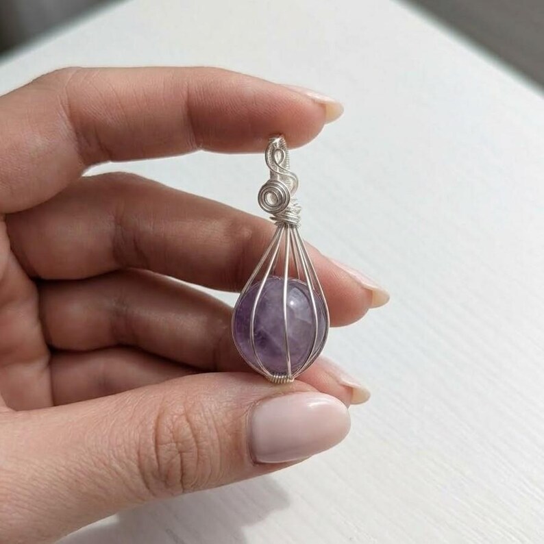 Elegant amethyst crystal ball pendant in sterling silver wire wrap, suitable for crown chakra activation and February birthstone gifting.