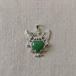 Close-up of natural green aventurine gemstone set in detailed silver heart crown pendant, elegant handmade spiritual necklace for women.