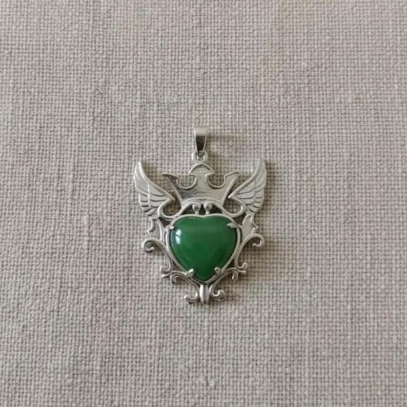 Close-up of natural green aventurine gemstone set in detailed silver heart crown pendant, elegant handmade spiritual necklace for women.