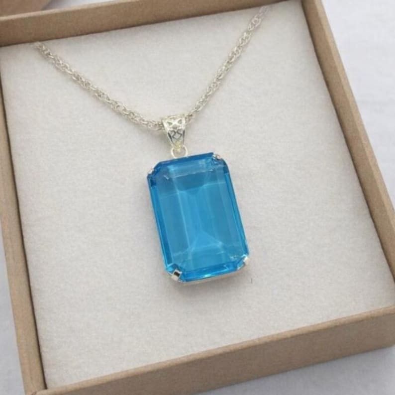 Natural Swiss blue topaz emerald cut pendant necklace set in sterling silver prong setting, featuring vibrant sky blue gemstone brilliance, perfect December birthstone jewelry gift for women.