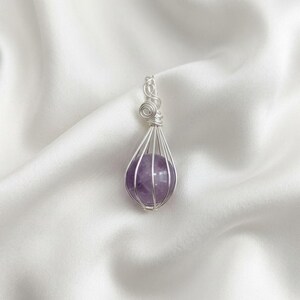 Amethyst healing crystal sphere pendant showcasing soft lavender and deep purple tones in elegant wire wrapped silver setting.