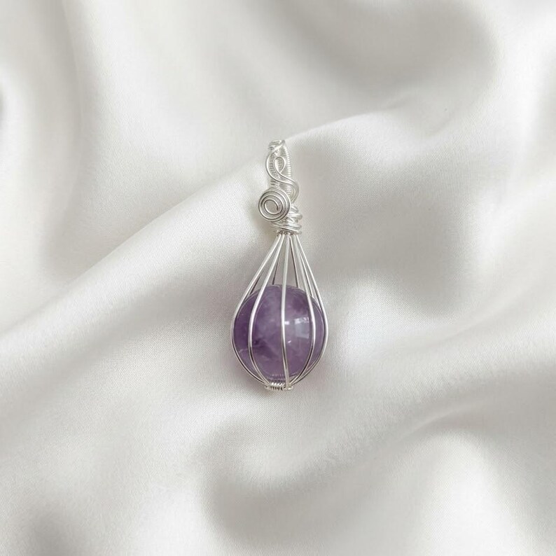 Amethyst healing crystal sphere pendant showcasing soft lavender and deep purple tones in elegant wire wrapped silver setting.
